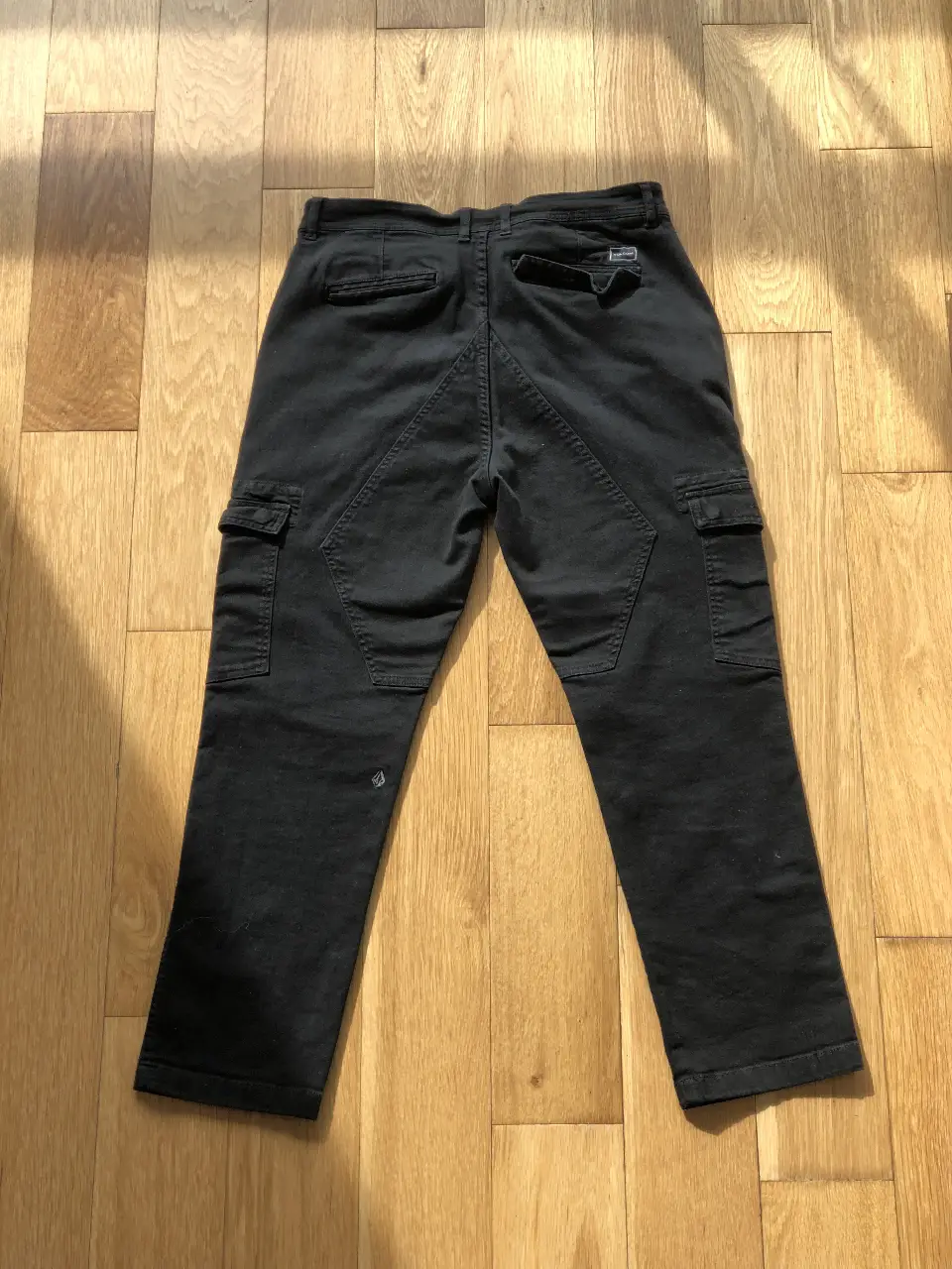 Pantalón cargo negro de hombre, con bolsillos laterales y detalle de costuras en la parte trasera. Talle 32, de la marca Volcom.