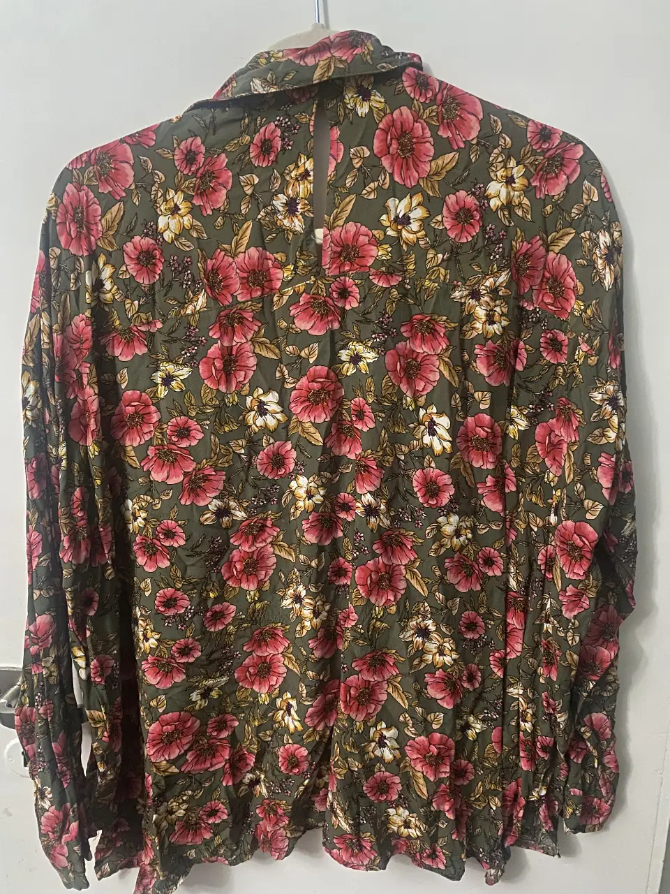 Camisa estampada con flores en tonos rosa y blanco sobre un fondo verde oscuro. Ideal para un look bohemio y casual.