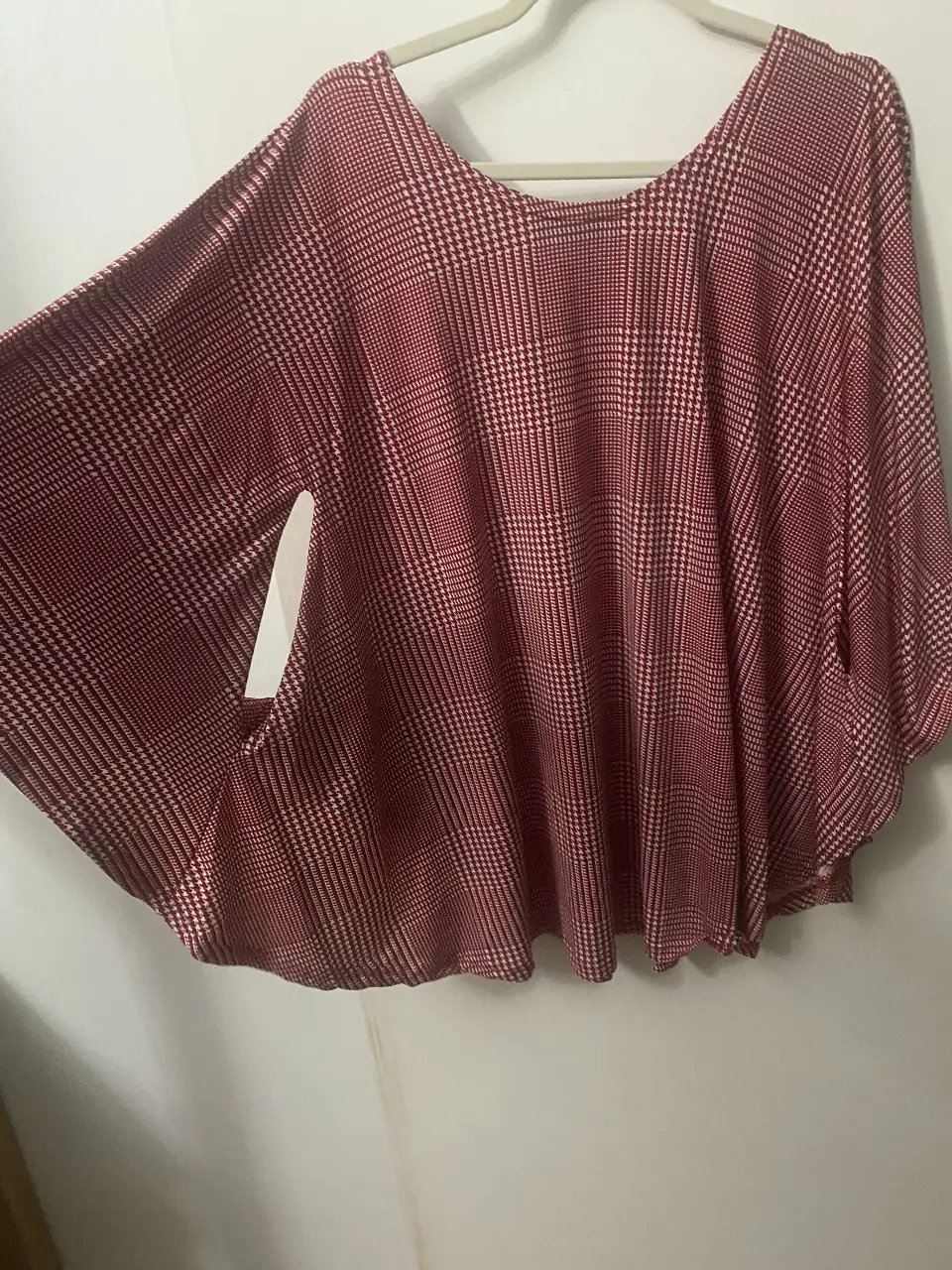 Blusa tipo poncho con estampado de cuadros en tonos rojo y blanco. Ideal para un look casual y cómodo.
