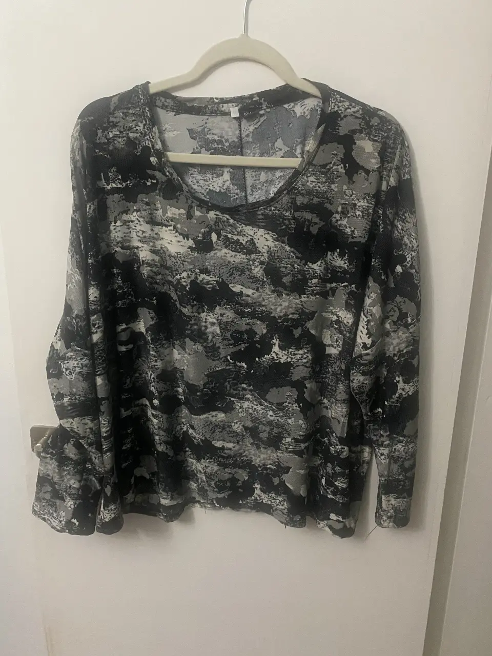 Remera de manga larga con estampado abstracto en tonos grises y negros. Ideal para un look casual y moderno.