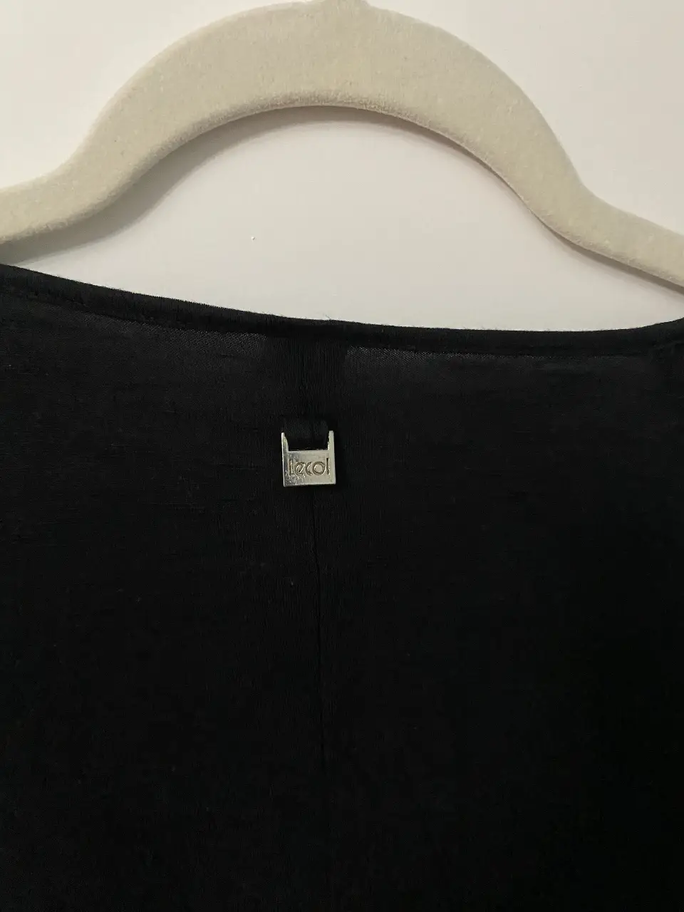 Blusa negra con mangas cortas con volados, ideal para un look elegante y femenino. Con detalle de etiqueta metálica en la parte trasera.