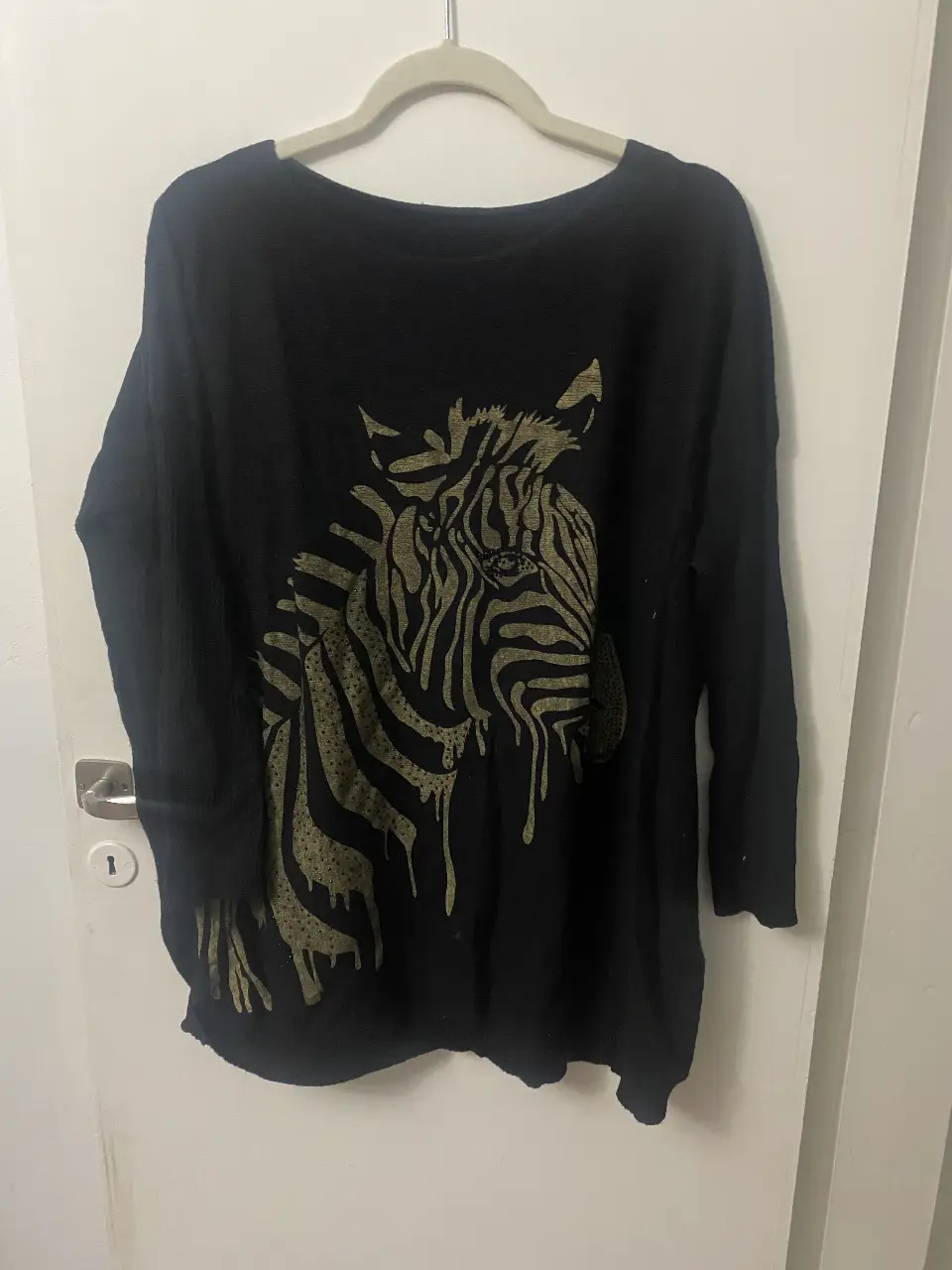 Sweater negro de manga larga con estampado de cebra en color dorado. Ideal para un look casual y cómodo.