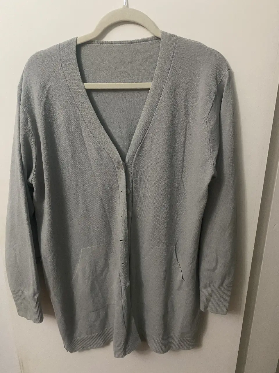 Cardigan largo de punto en color gris, con cuello en V y botones. Ideal para un look casual y cómodo.