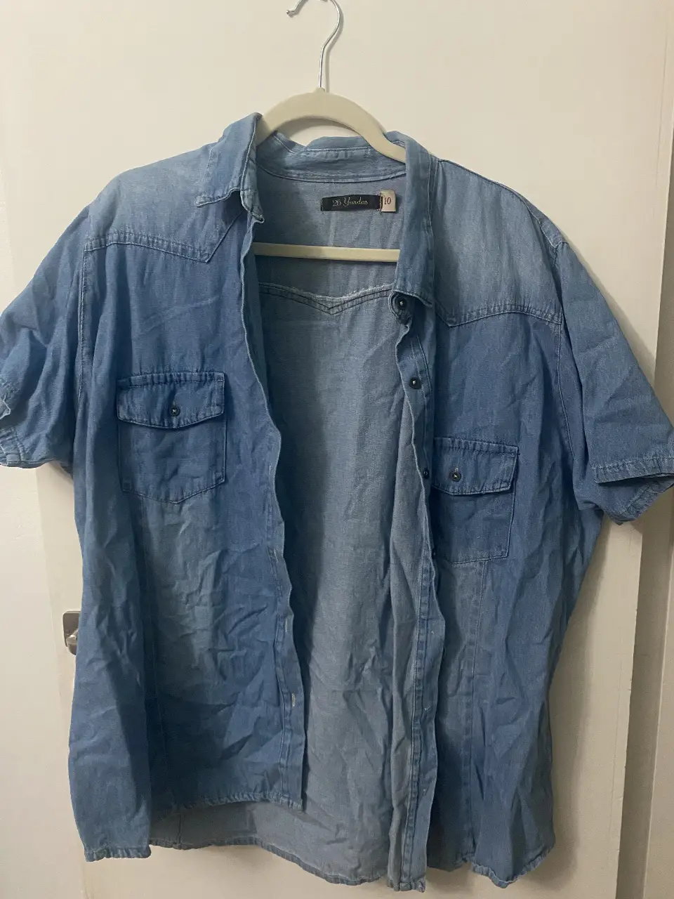 Camisa de jean azul, manga corta, ideal para un look casual y relajado. Perfecta para combinar con jeans o shorts.