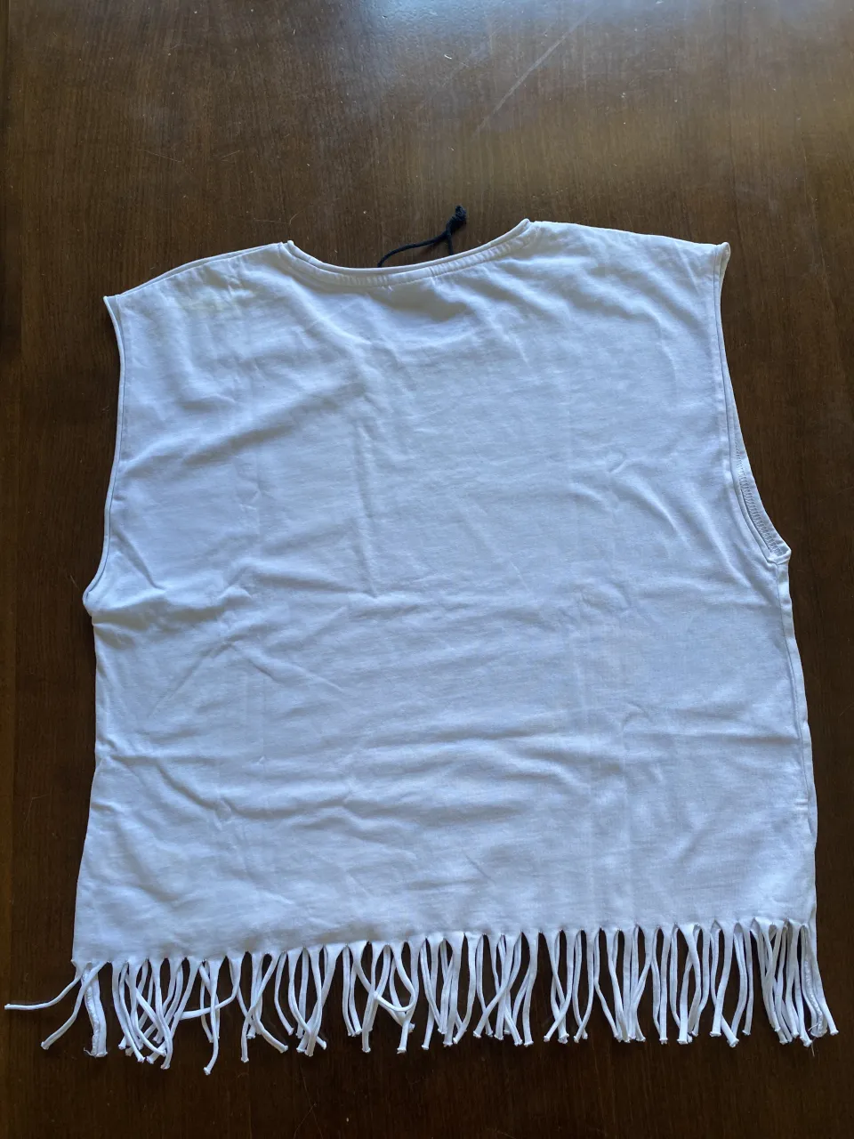 Musculosa blanca con tachitas plateadas y flecos en la parte inferior. Ideal para un look canchero y fresco.en la parte de atras tiene una manchita medio amarillenta pero no es notable ( en la foto se puede apreciae bien la imperfeccion . 