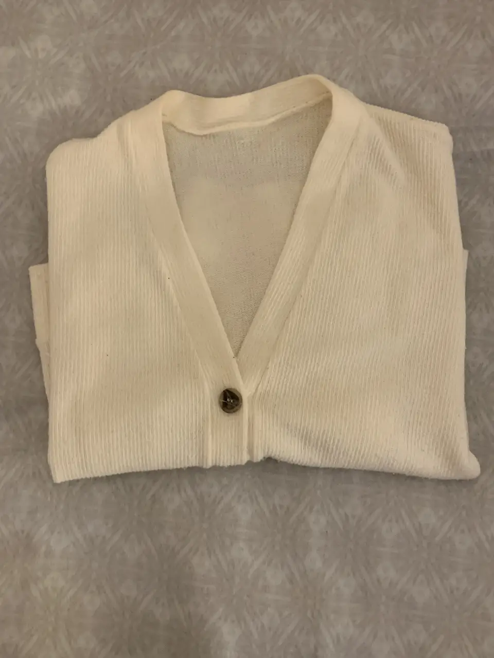 Cardigan tejido de punto en color crudo, con cuello en V y tres botones . Ideal para un look casual y cómodo.