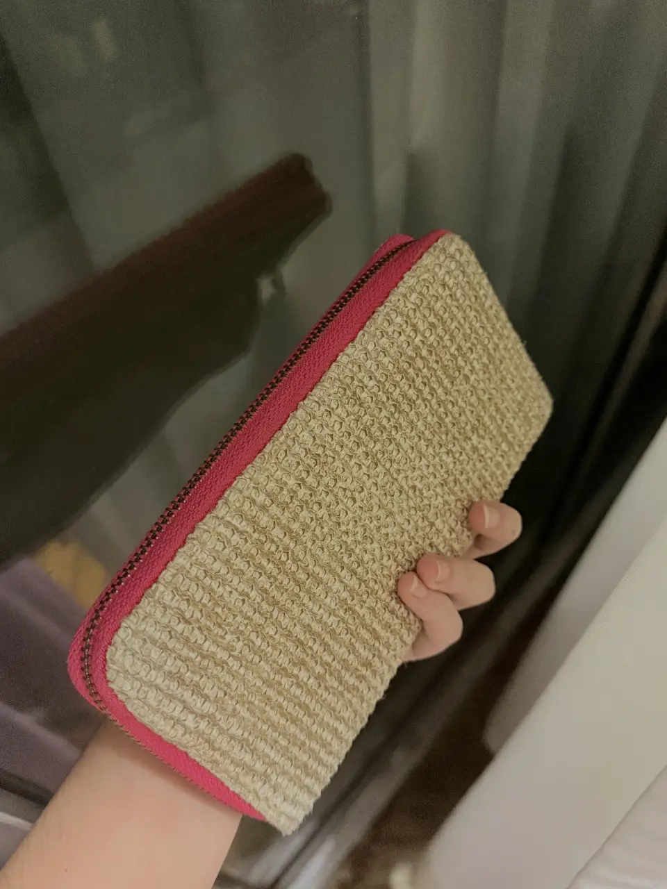 Billetera  con diseño tejido en color dorado y detalles en fucsia. Cuenta con cierre y múltiples compartimentos internos.