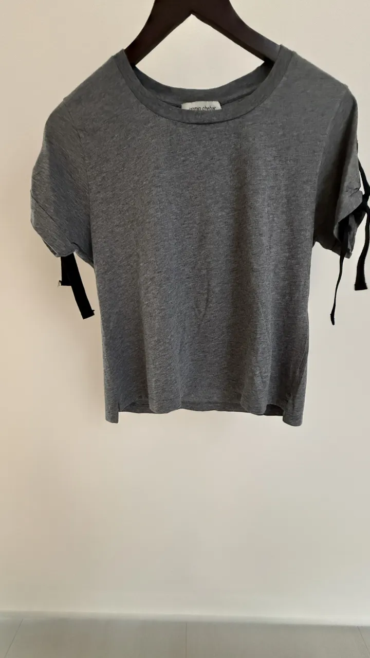 Remera gris de Jazmin Chebar con detalles de lazos en las mangas. Ideal para un look casual y chic.

Talle 1 de la marca. Medidas en la ultima foto