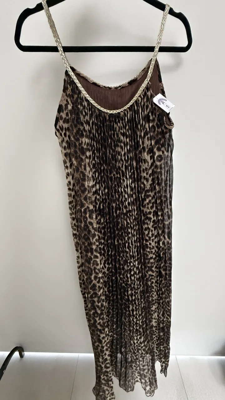 Vestido largo con estampado de leopardo y tiras trenzadas doradas en los hombros. Posee un detalle de plisado en toda la prenda. Plisado. detalle, las tiras son de cuerina dorada trenzada, presenta desgaste, pueden cambiarse