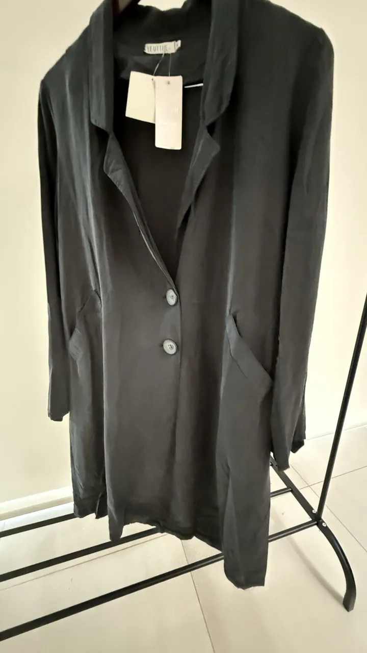 Saco largo de color negro, con dos botones al frente y bolsillos laterales. Cuello solapa.  La tela es liviana, para media estacion . Tiene boton para acprtar las mangas.  medidas en la publicación 