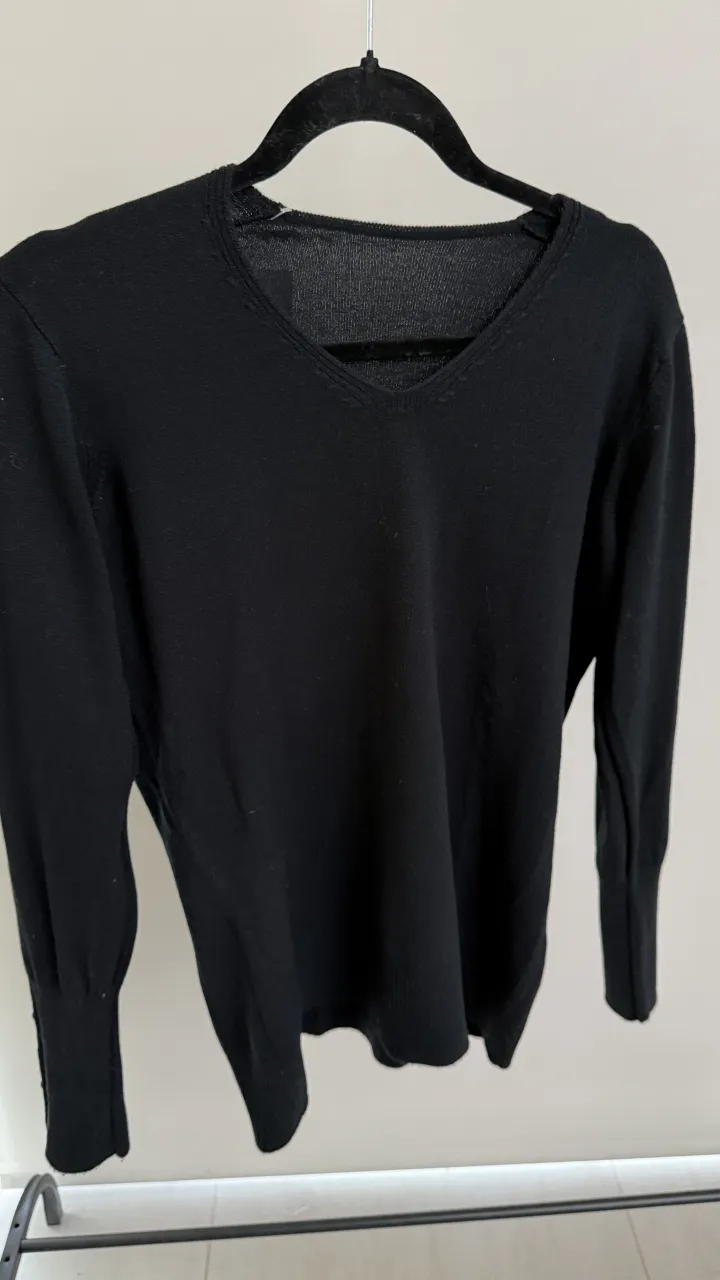 Sweater negro de manga larga con cuello en V y detalles de botones en los puños. talle unico abarca hasta un M
