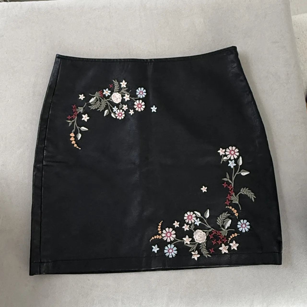 Pollera negra corta con bordados florales en los laterales. Diseño de flores y hojas en tonos blanco, rosa, rojo, azul y verde.

Marca VER, talle S. Medidas: cintura 40, cadera 50, largo 45