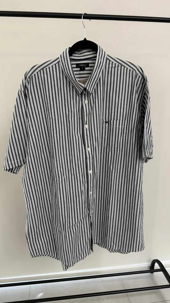 Camisa a rayas verticales con mangas cortas y bolsillo en el frente. Posee botones al tono. Marca Legacy, talle 5, medidas en la publicación 