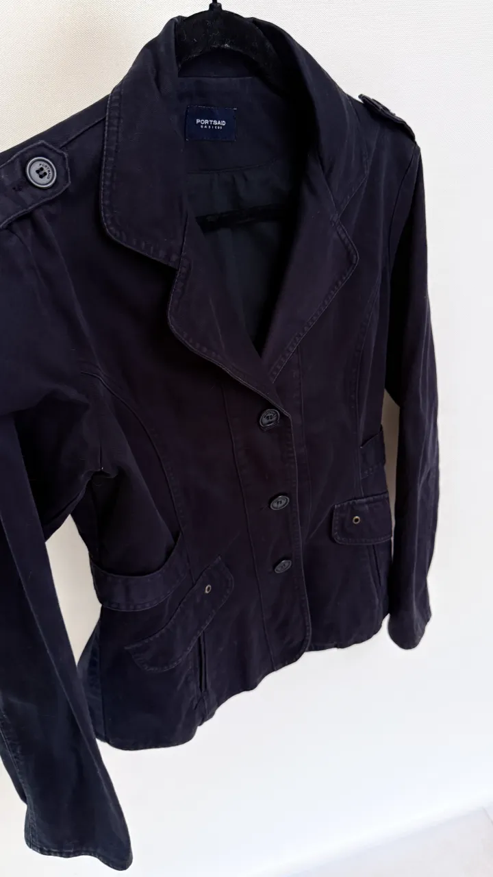 Chaqueta de gabardina negrocon botones al frente y bolsillos. Tiene solapas y detalles de botones en los hombros.
marca Portsaid, talle M. Al ser negro, no sale bien la imagen.
Medidas: hombros  42, sisa 50 , largo total  62, largo mangas 58