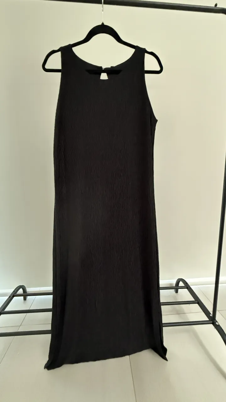 Vestido negro largo, sin mangas, con escote redondo y detalle de botón en la espalda. Posee una textura acanalada en toda la tela. Marca Ted Bodin, nuevo con etiqueta. ver medidas en publicacion, va para un M 