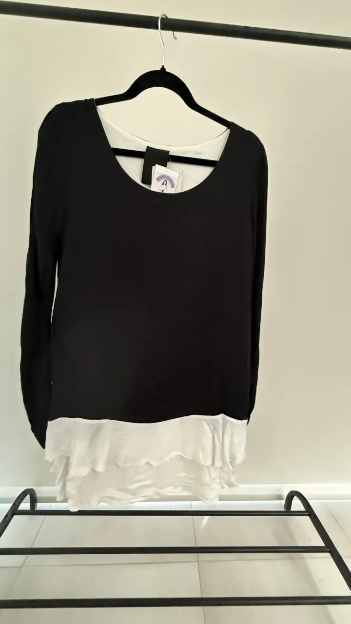 Vestudo corto manga larga de dos tonos, negro y blanco. La parte inferior presenta un diseño de volados asimétricos.
Marca Allo Matinez, Talle 46 de la marca, va para un M, medidas en la publicación 