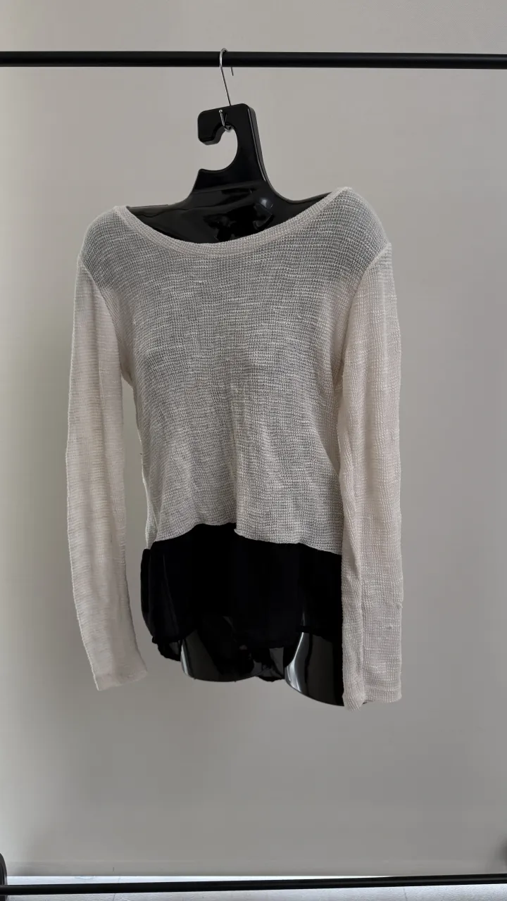 swetaer manga larga de tejido liviano color blanco roto con detalle de tela negra en la parte inferior. 