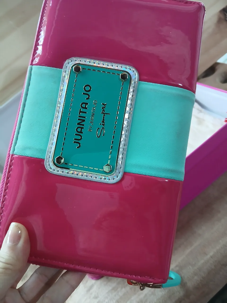 Billetera larga de charol fucsia con detalles en turquesa. Tiene múltiples compartimentos internos y cierre completo. Incluye bolsa de tela y caja original de la marca Juanita Jo. Estado impecable,como se ve. solo tiene  un detalle enganchado como se ve en la última foto.