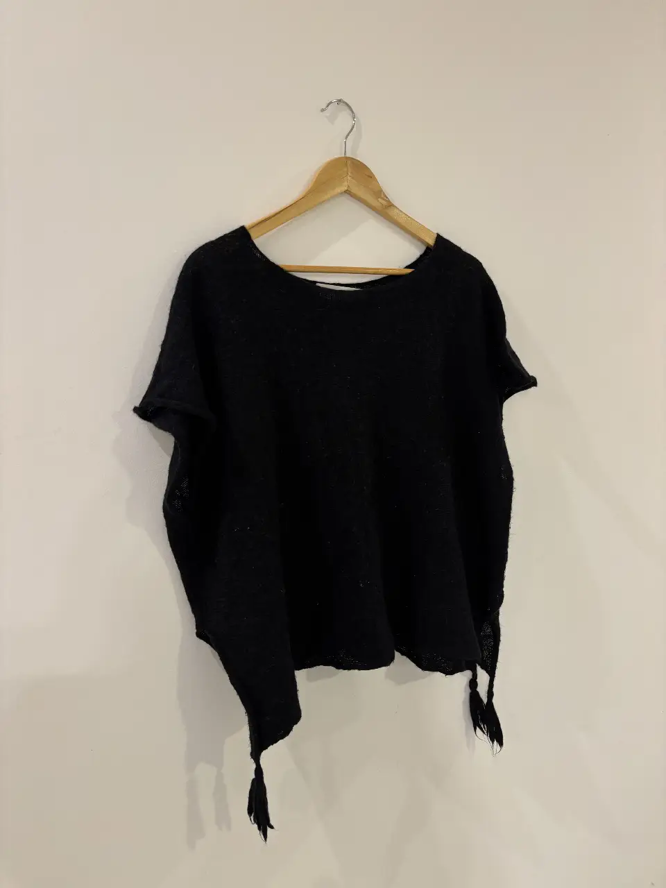 Sweater negro de tejido liviano, con mangas cortas y detalles de flecos en los bordes. 