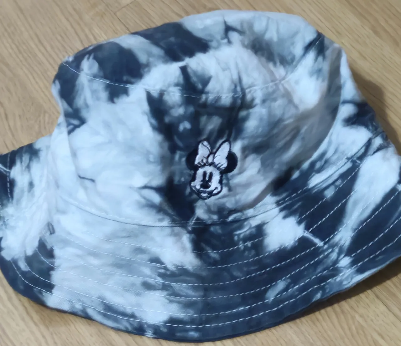 Sombrero bucket tie dye en tonos grises y blancos, con estampado de Minnie Mouse. Ideal para un look casual y moderno.