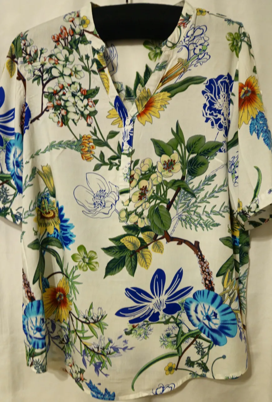 Blusa de mujer con estampado floral en tonos azules, amarillos y verdes sobre fondo blanco. Cuello en V y mangas cortas. Ideal para un look fresco y primaveral.Brasil.