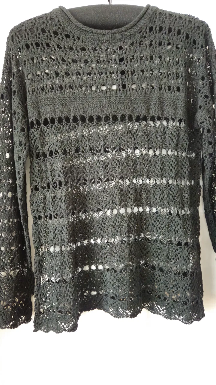 Sweater largo de tejido calado en color negro, ideal para un look casual y moderno. Perfecto para combinar con diferentes outfits.