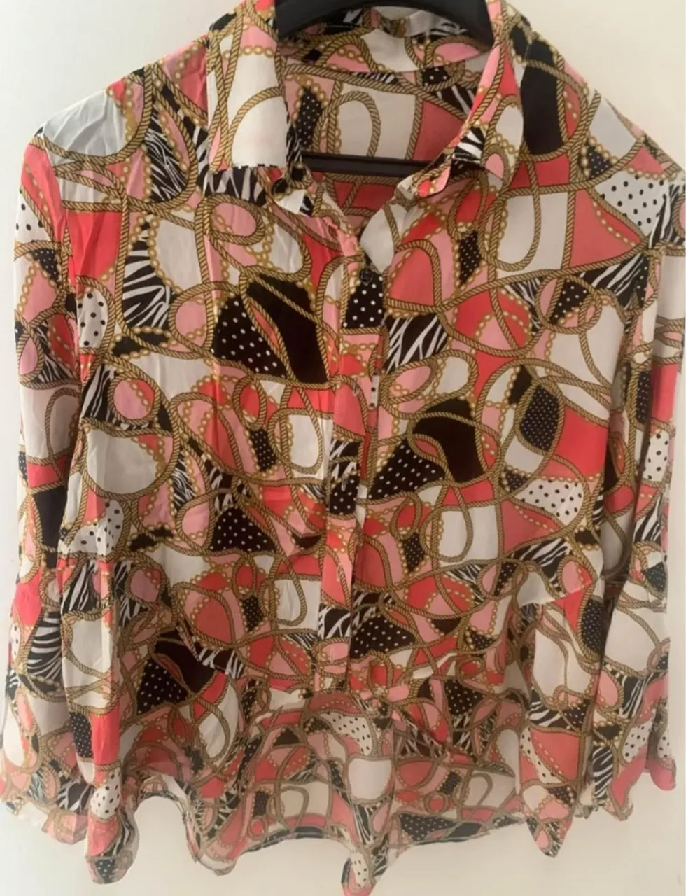 Camisa estampada con diseño de cadenas y figuras geométricas en tonos coral, negro y blanco. Ideal para un look moderno y con estilo.
