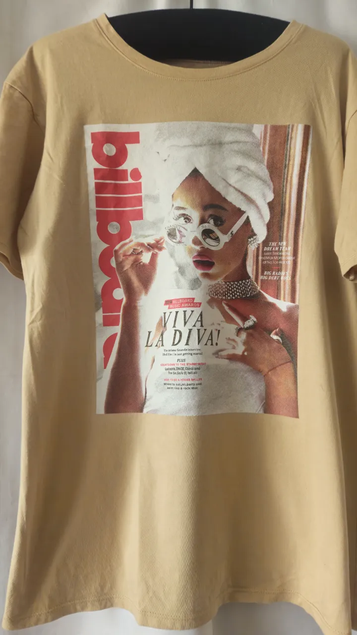 Remera de algodón color amarillo mostaza con estampado de revista Billboard. Diseño con imagen de mujer con gafas y pañuelo. Ideal para un look casual y con onda. Marrón claro.
