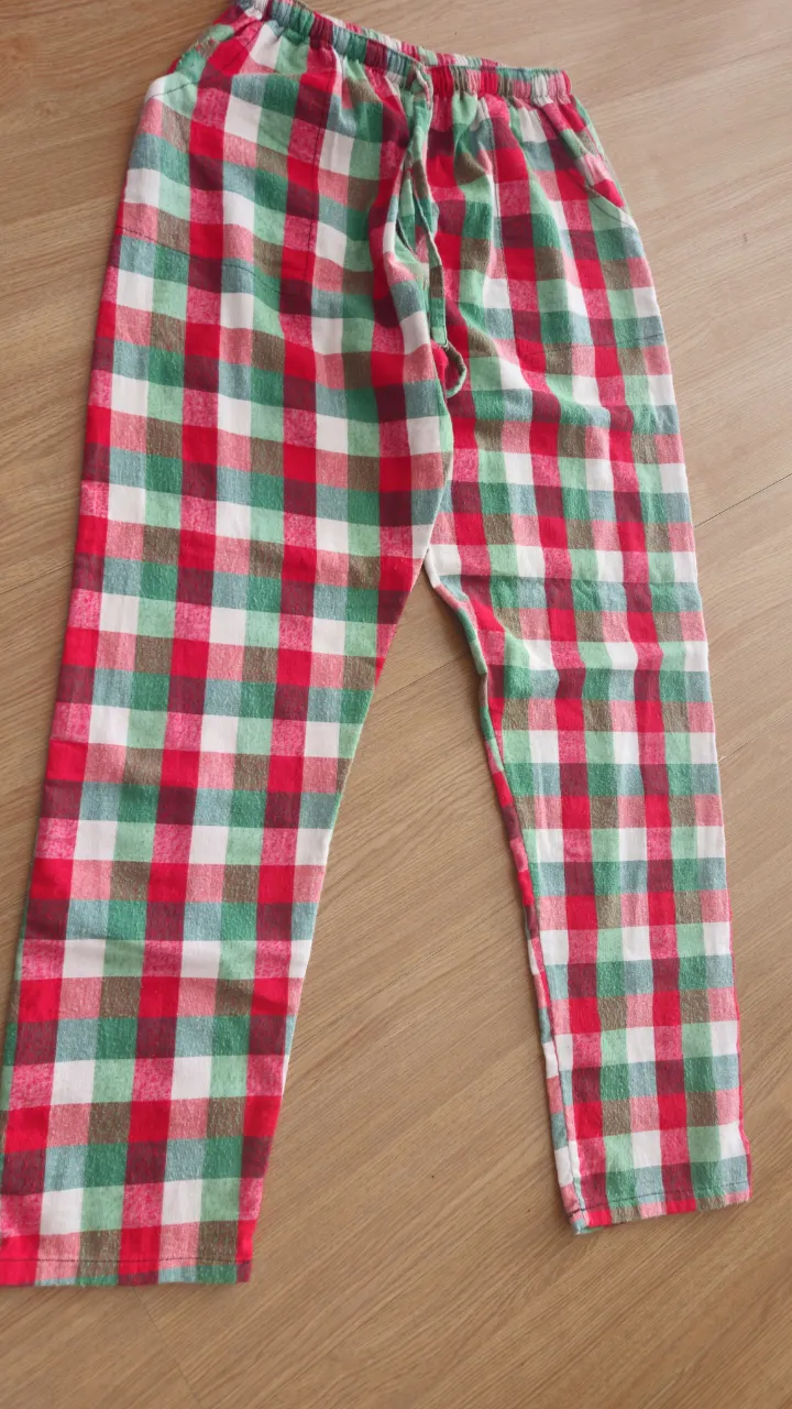 Pantalón de pijama a cuadros en rojo, verde y blanco. Ideal para estar cómodo en casa. Confeccionado en tela suave y con cintura ajustable.