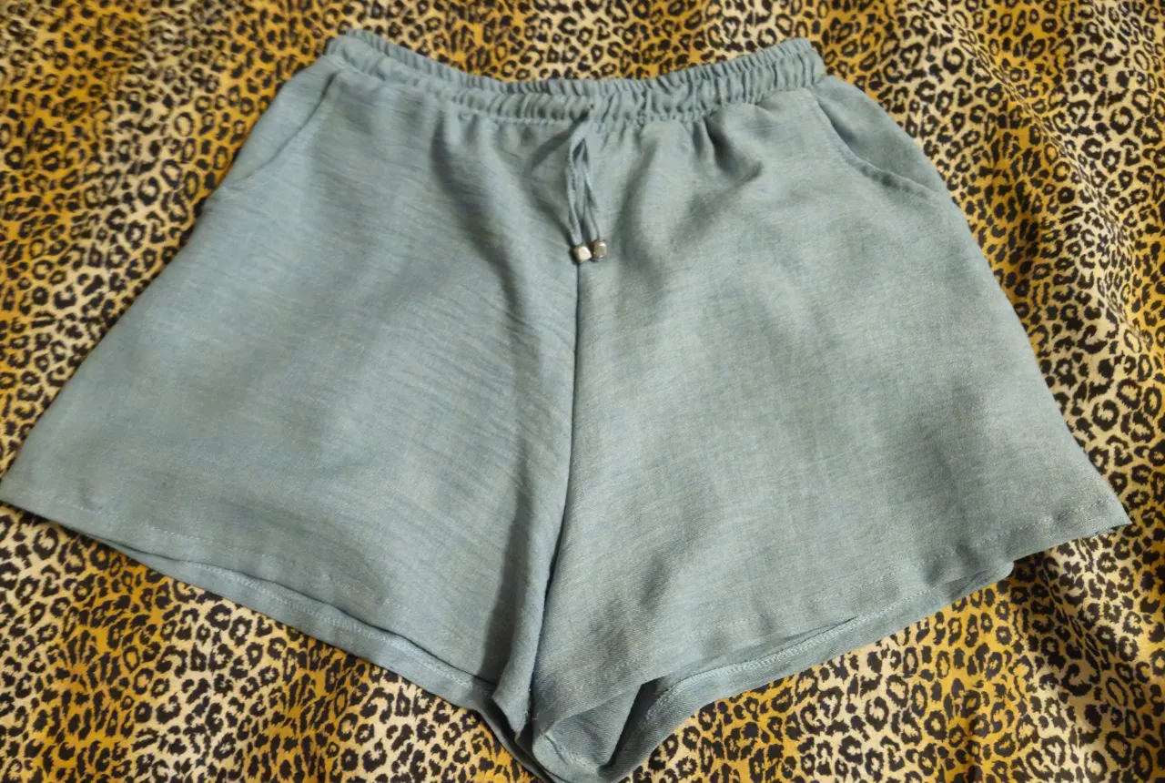 Short de tela tejida celeste con cintura elastizada y cordón. Bolsillos laterales.