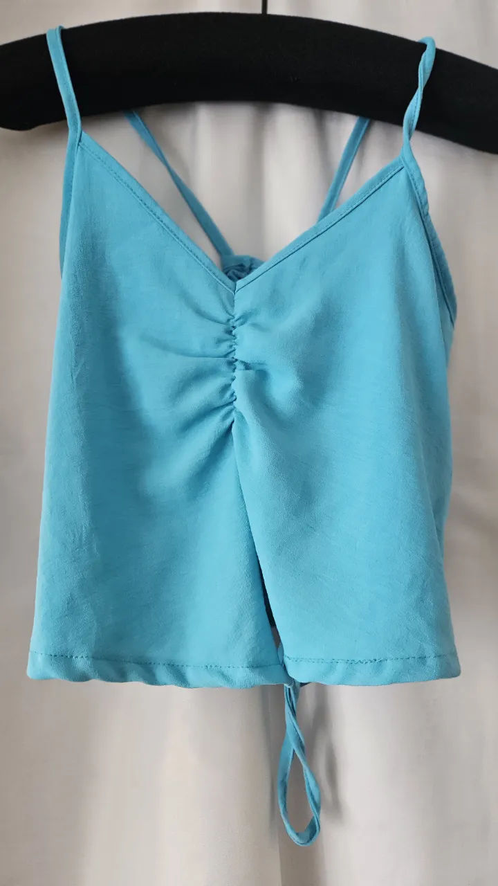Top de mujer, color turquesa, con detalle fruncido en el frente y tiras cruzadas en la espalda. Ideal para un look fresco y moderno.
