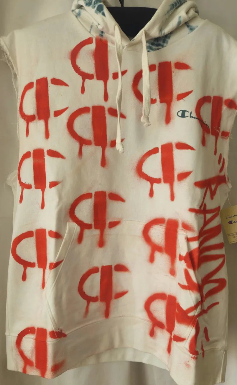 Buzo canguro Champion blanco con intervenciones de pintura roja y detalles en la capucha. Estilo streetwear y vintage.