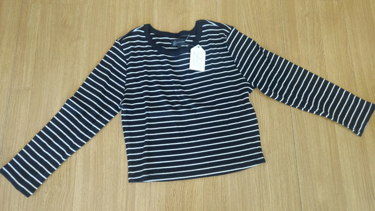Remera de manga larga a rayas horizontales en blanco y negro, ideal para un look casual y moderno. Confeccionada en tejido suave y cómodo, perfecta para combinar con jeans o pantalones.