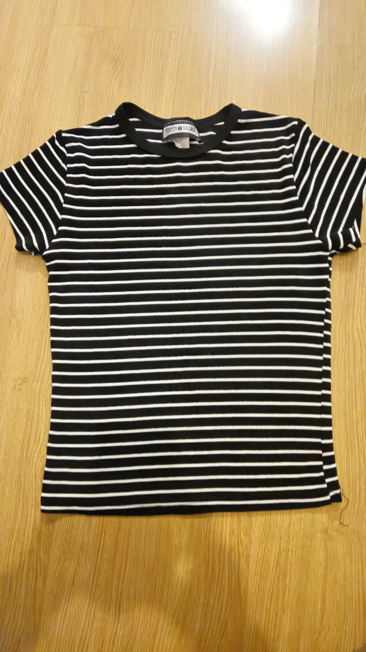 Remera de mujer a rayas horizontales en blanco y negro, de manga corta y cuello redondo. Ideal para un look casual y versátil.