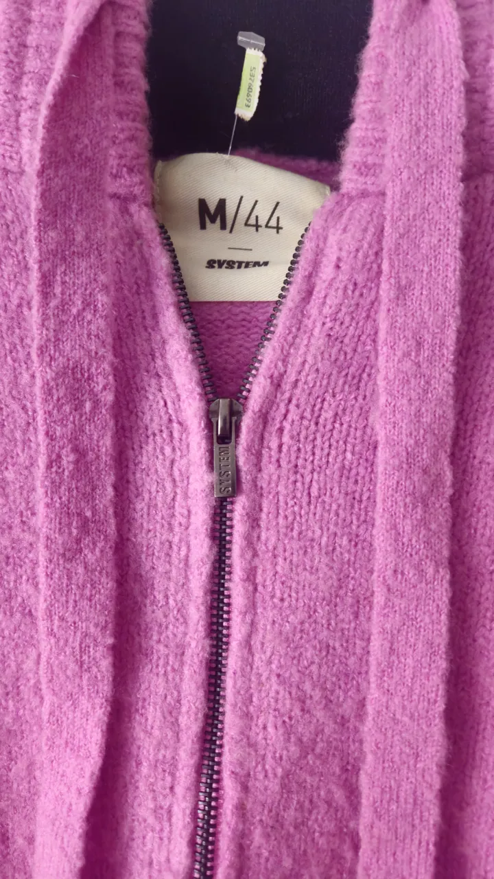 Buzo con capucha y cierre frontal, de color rosa. Ideal para un look casual y cómodo.