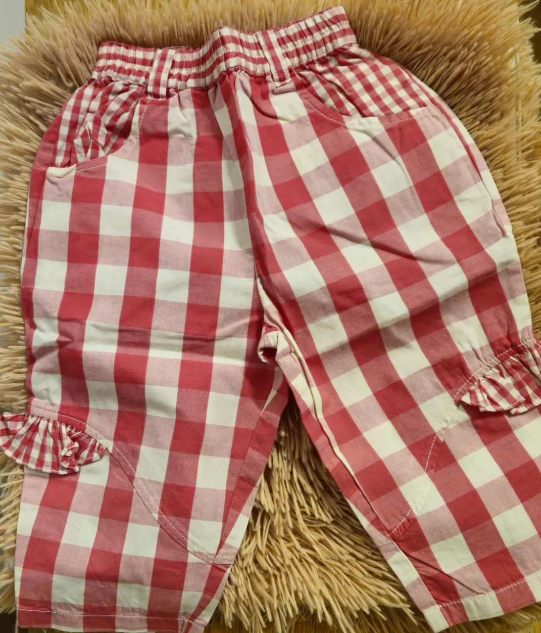 Pantalón corto de niña, a cuadros rojos y blancos, con cintura elastizada y detalles de volados en los bolsillos. Ideal para un look fresco y cómodo. Italia.