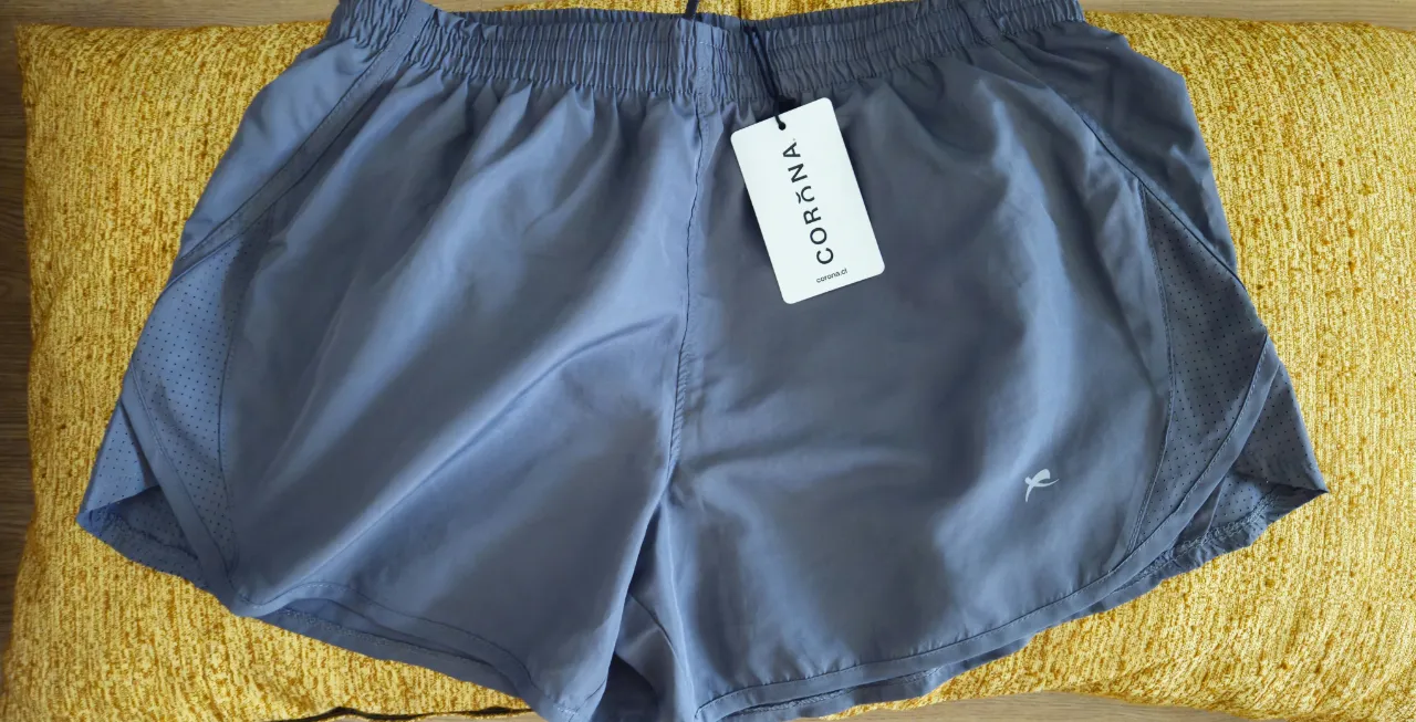 Shorts deportivos grises con detalles de ventilación en los laterales. Ideales para entrenar o para un look casual y cómodo. Cuentan con cintura elástica y cordón ajustable para un calce perfecto. El tejido es ligero y de secado rápido.