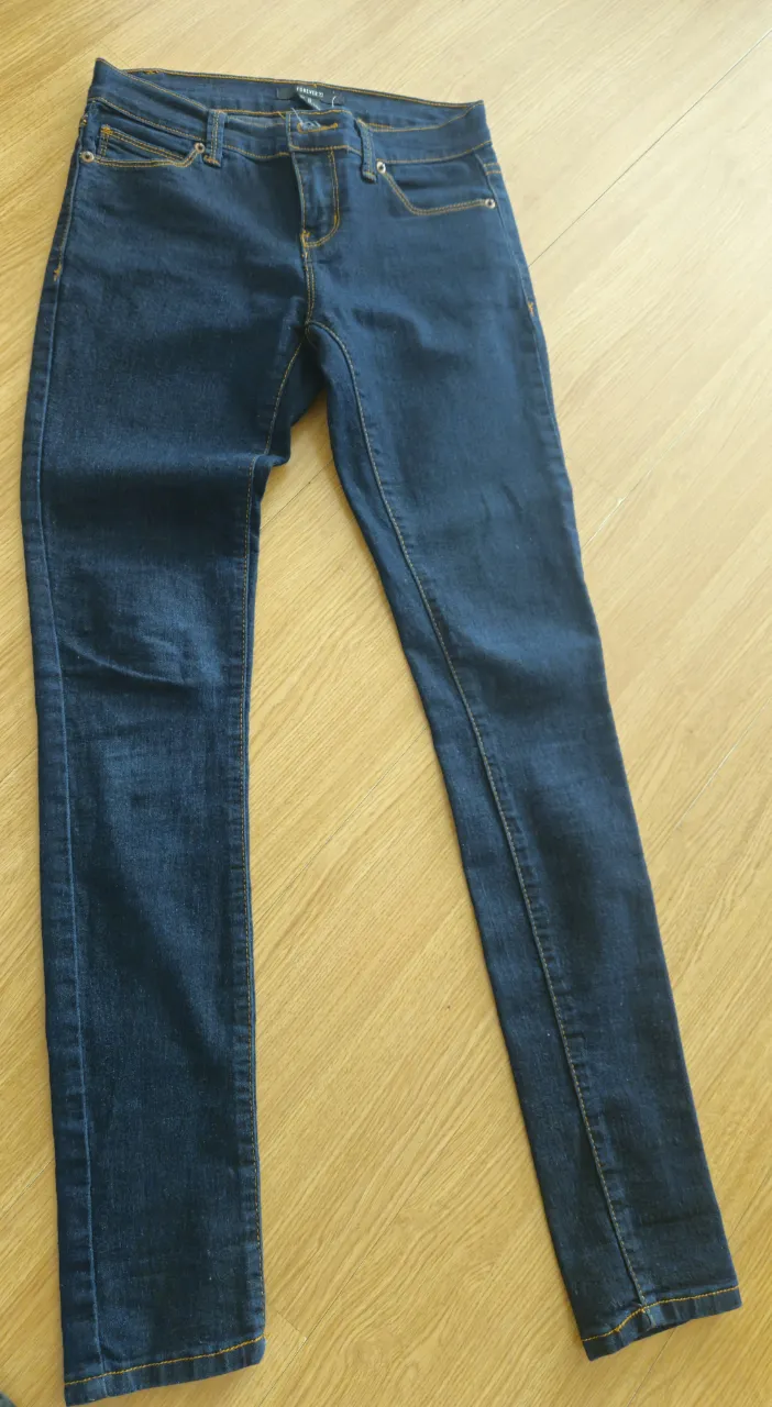 Jeans de mujer Forever 21, tiro medio, corte recto, color azul oscuro, con detalles de costura en amarillo. Talle 24 US.