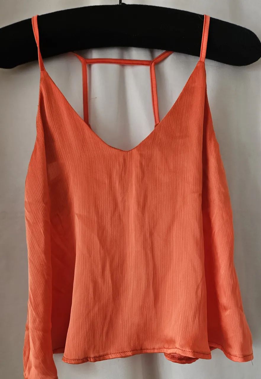 Top naranja con tiras finas y espalda descubierta. Ideal para un look fresco y moderno.