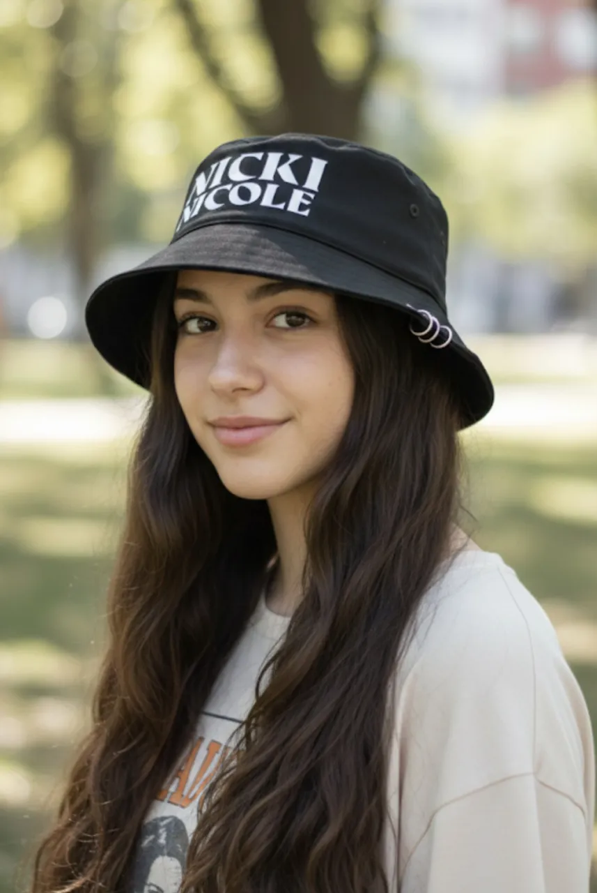 Sombrero tipo bucket hat negro con detalles de argollas plateadas y estampa "NICKI NICOLE" en blanco. ¡Ideal para completar tu look urbano! Tengo 3 o 4 unidades, nuevos.