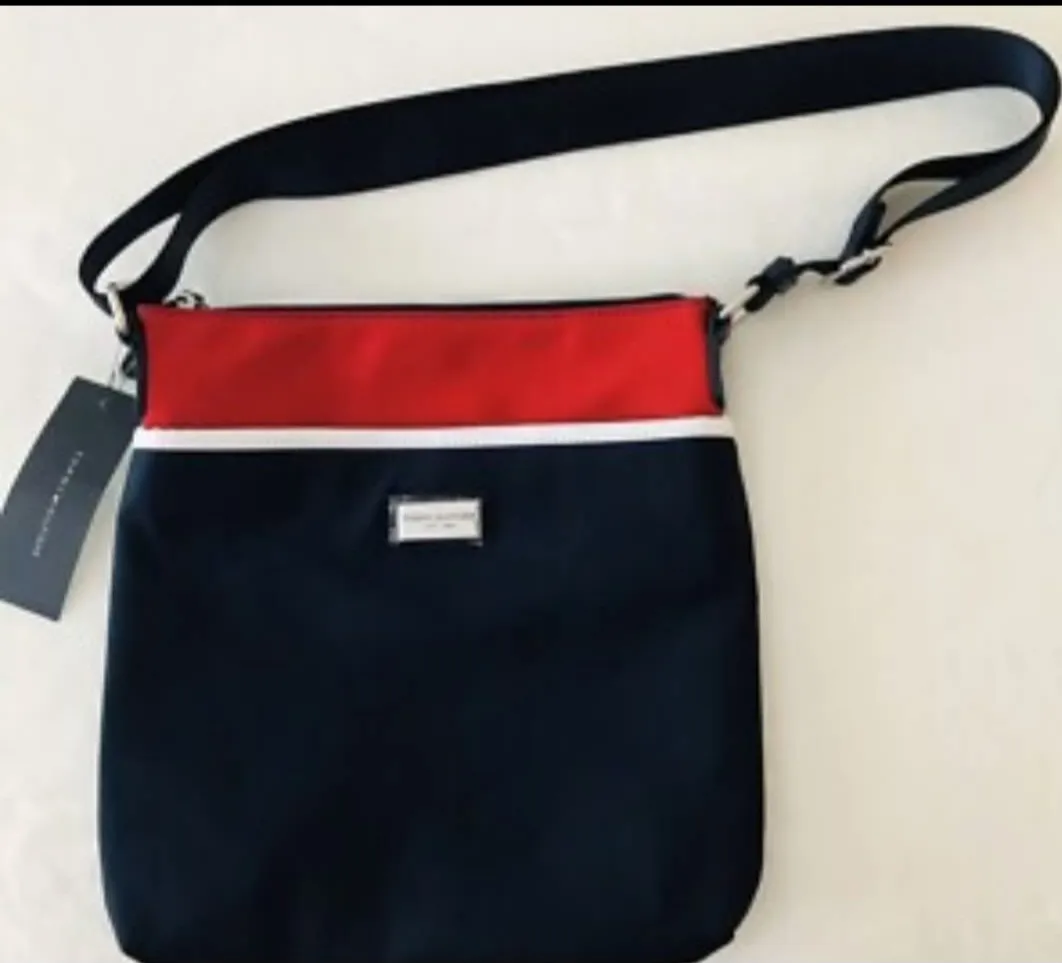 Bandolera Tommy Hilfiger en color azul marino con detalles en rojo y blanco. Posee correa ajustable y un pequeño logo metálico. Ideal para llevar tus esenciales con estilo. Medida 30*25 cm.