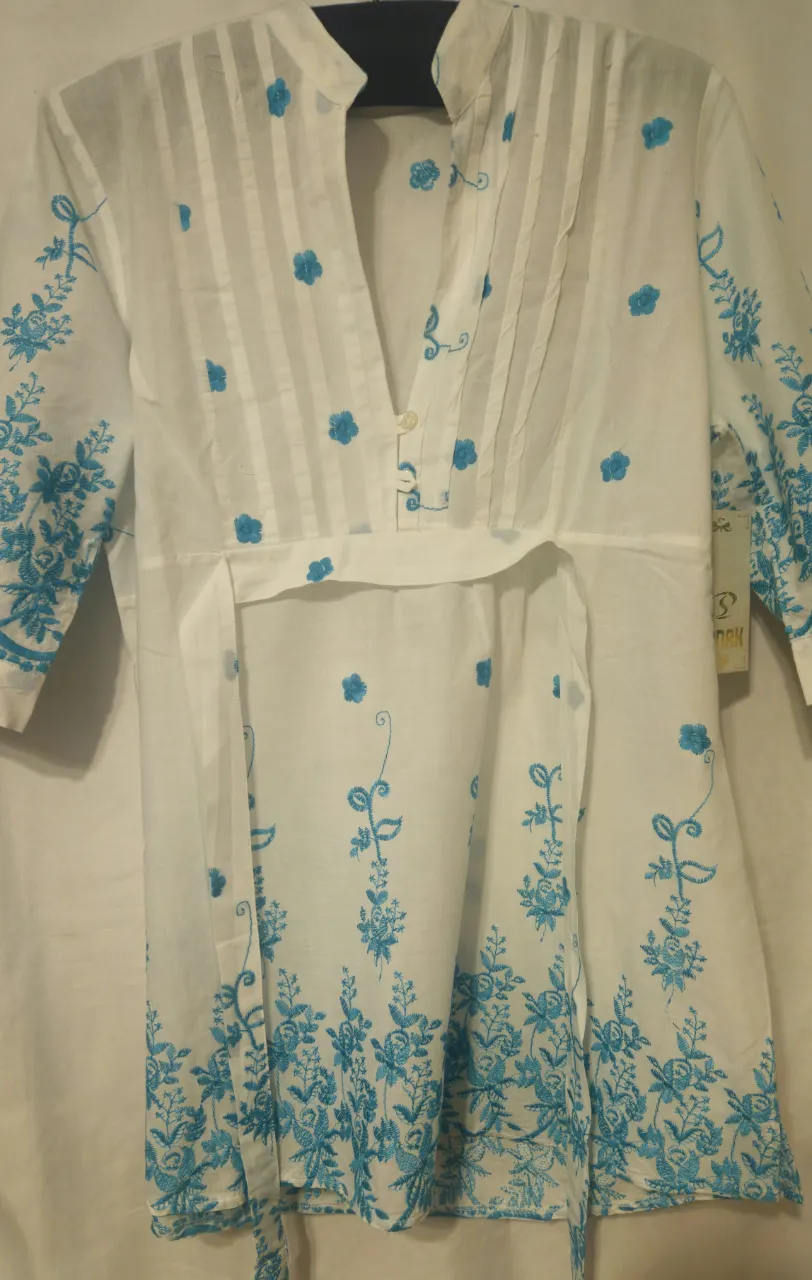 Blusa blanca con bordados florales en azul. Diseño con cuello en V y detalles plisados, ideal para un look fresco y femenino. Sisa a sisa 46 cm, largo 74 cm.