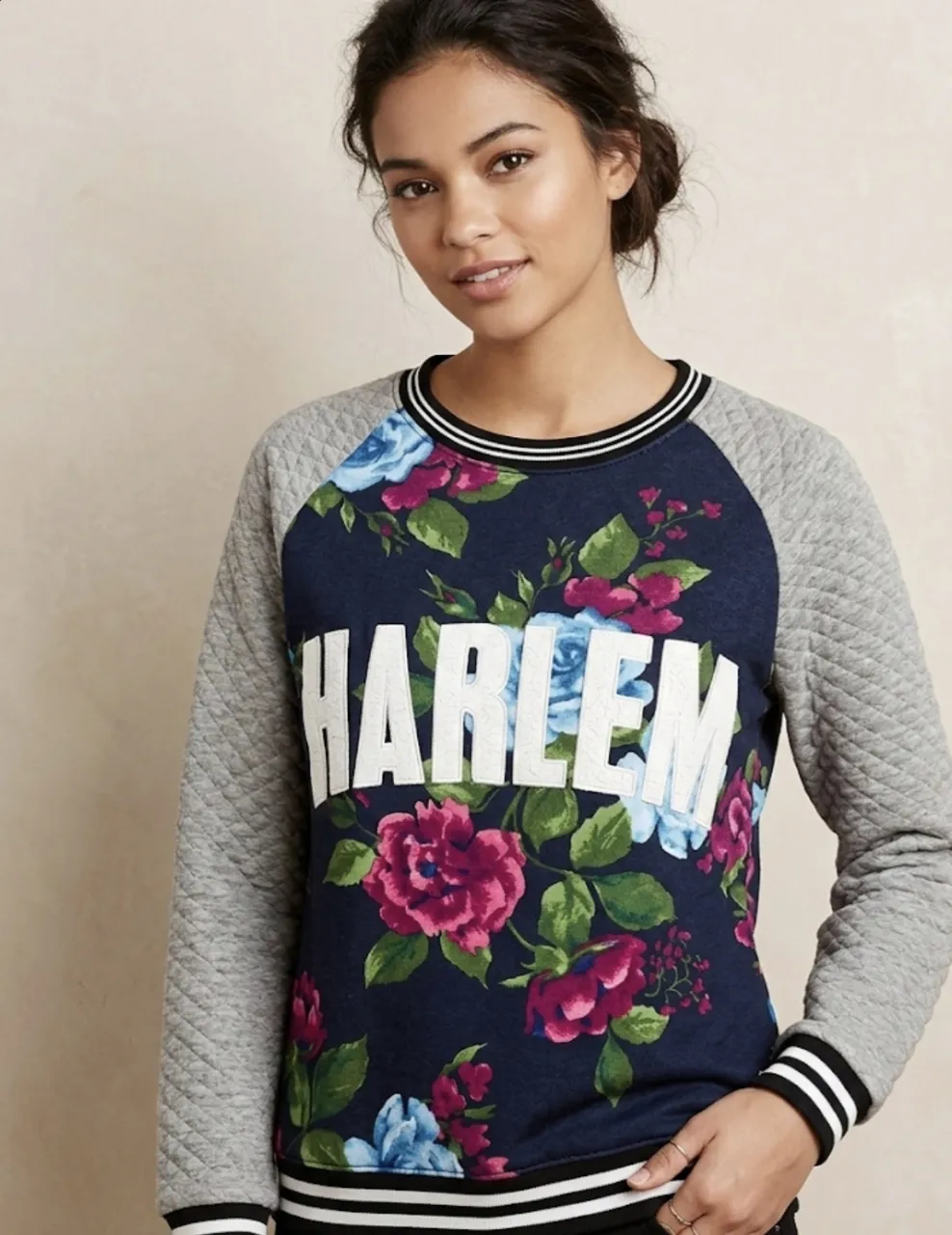 ¡Impresionante buzo con estampa floral y la palabra "HARLEM" en el frente! Las mangas y la espalda son de un gris matelaseado, con puños y cuello a rayas. ¡Un toque urbano y chic para tu look!