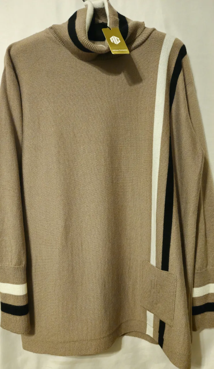 Sweater de cuello alto en color marrón con detalles en blanco y negro. Diseño con bolsillo y detalles en las mangas. Ideal para un look casual y abrigado.
