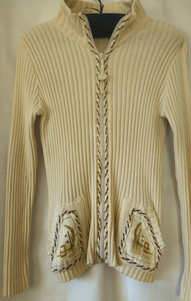 Sweater de lana tejido con cierre y bolsillos. Detalles bordados en los bolsillos y en el cierre. Marca Tiquichuela.