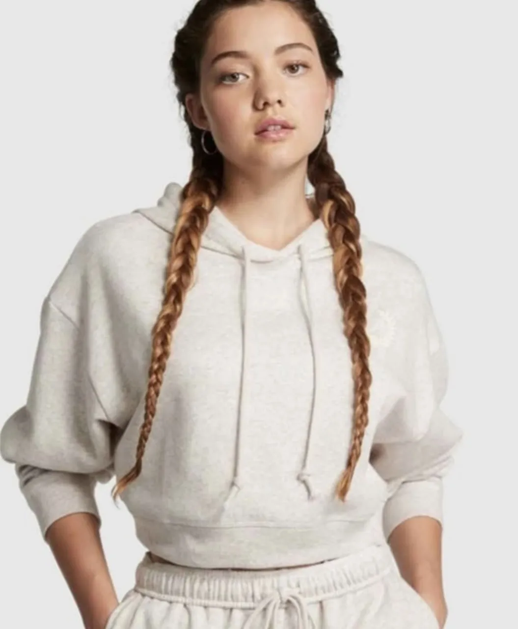 Buzo crop con capucha y cordones. Diseño liso en color crudo.