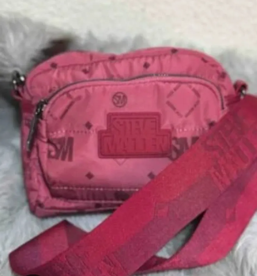 Bandolera Steve Madden roja con estampado del logo de la marca. Cuenta con correa ajustable y bolsillo frontal con cierre. Ideal para llevar tus esenciales con estilo. Monedero , medida 26*18*8 cm .