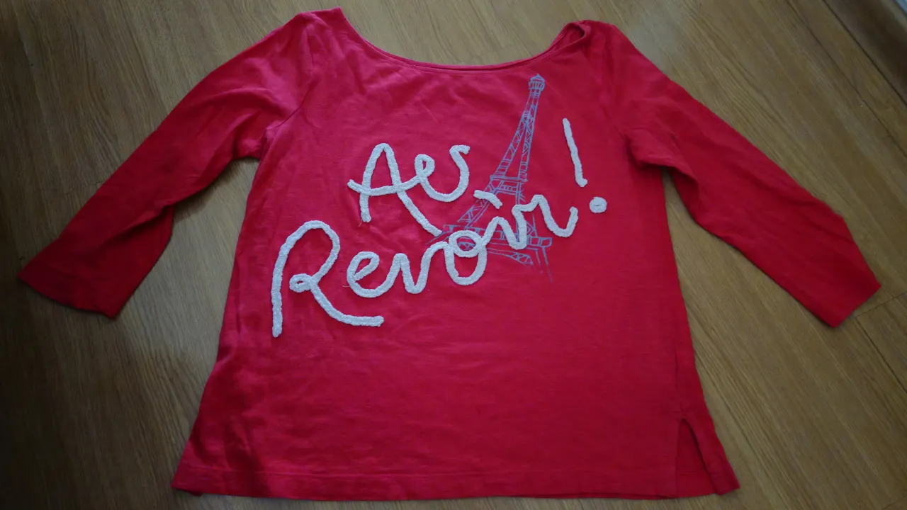 Remera manga larga color fucsia con estampa de la Torre Eiffel y la frase "Au Revoir!". Ideal para un look casual y canchero.