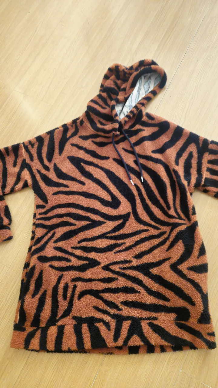 Buzo canguro con estampado de tigre en tonos naranja y negro. Ideal para un look casual y canchero. Perfecto para el invierno.