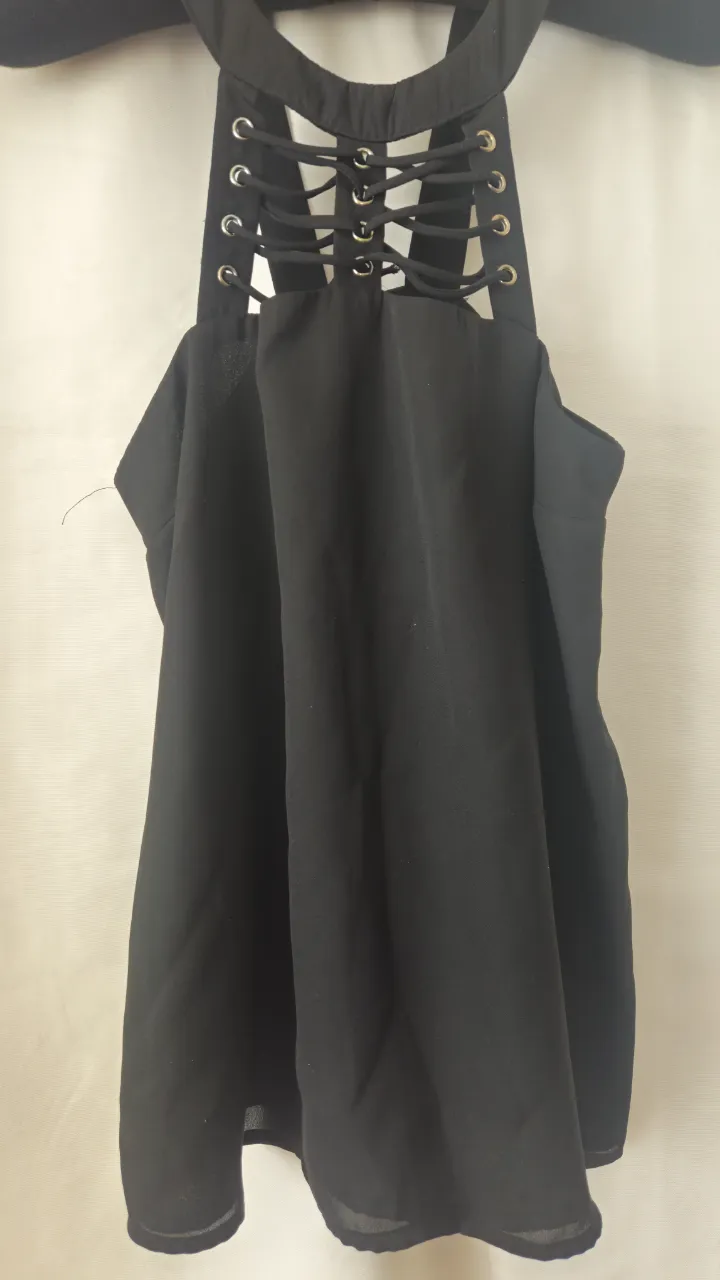 Top negro con detalle de tiras en la espalda y escote halter. Ideal para un look moderno y audaz.